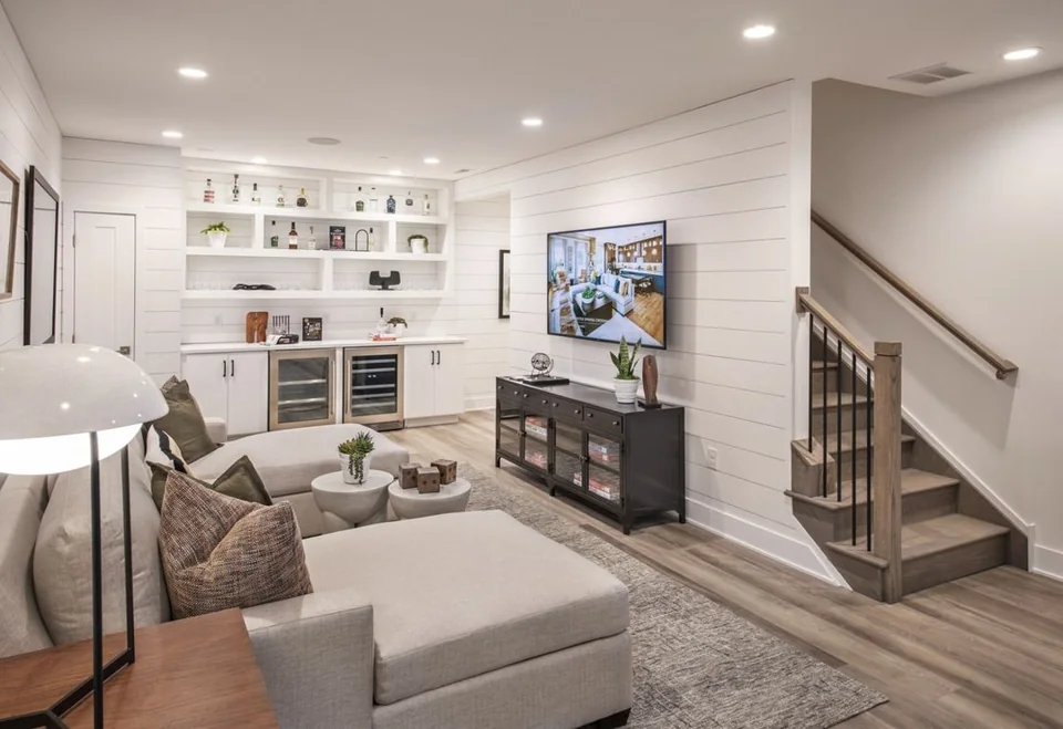 Finished basement living space with built-in shelving, a bar, TV wall and staircase